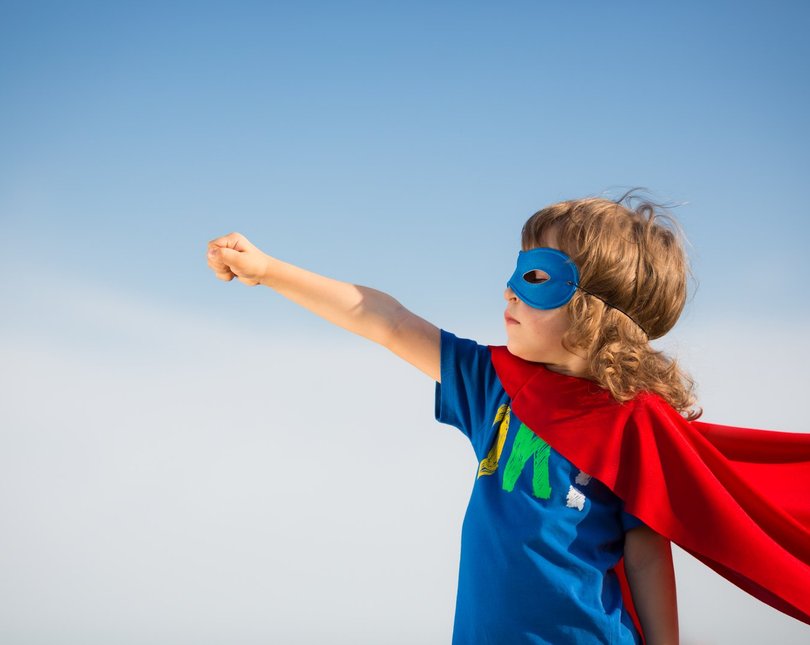 Child dressed as a super hero against a blue sky