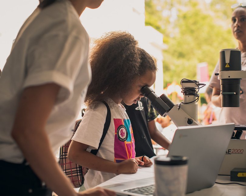 A young girl looking into a microscope
