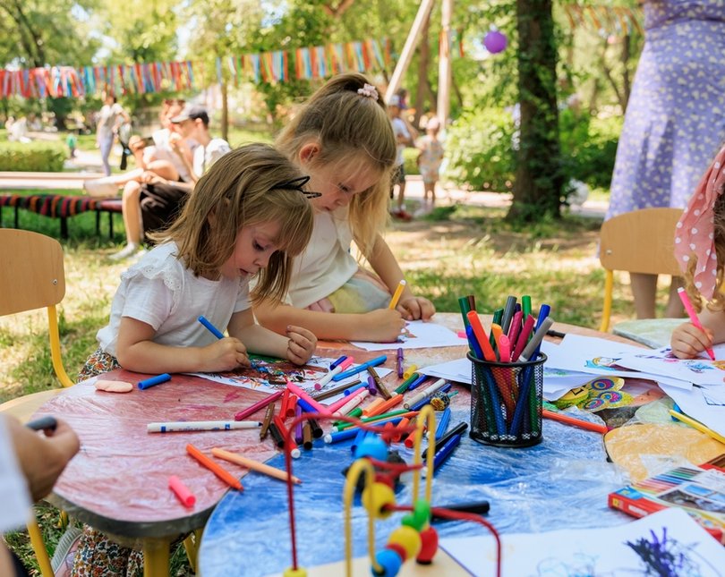 Two young girls drawing with crayons in a garden