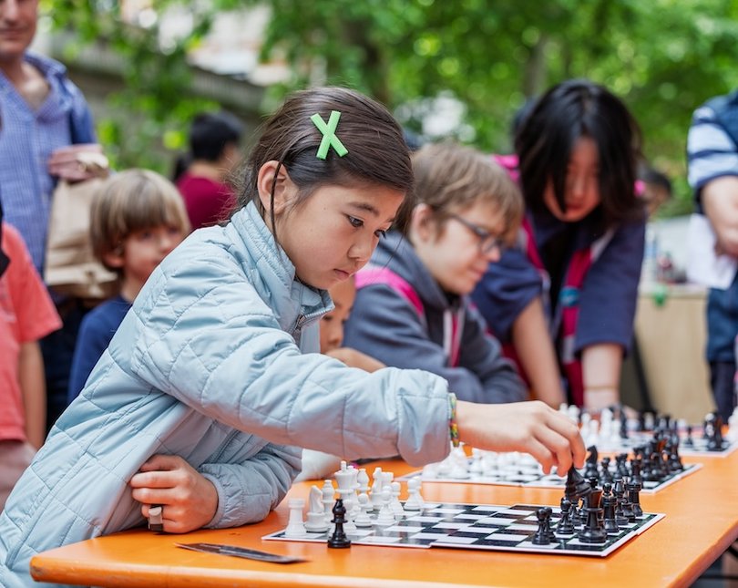 Young girl playing chess outside