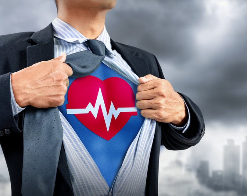Businessperson revealing a superhero heart health emblem beneath their suit jacket.