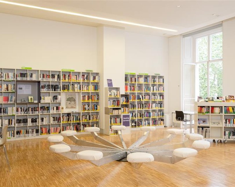 A library with books and a large desk in the centre