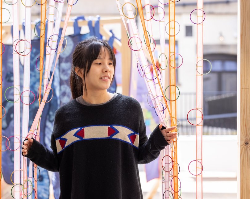 A young woman walking through hanging strips of cloth