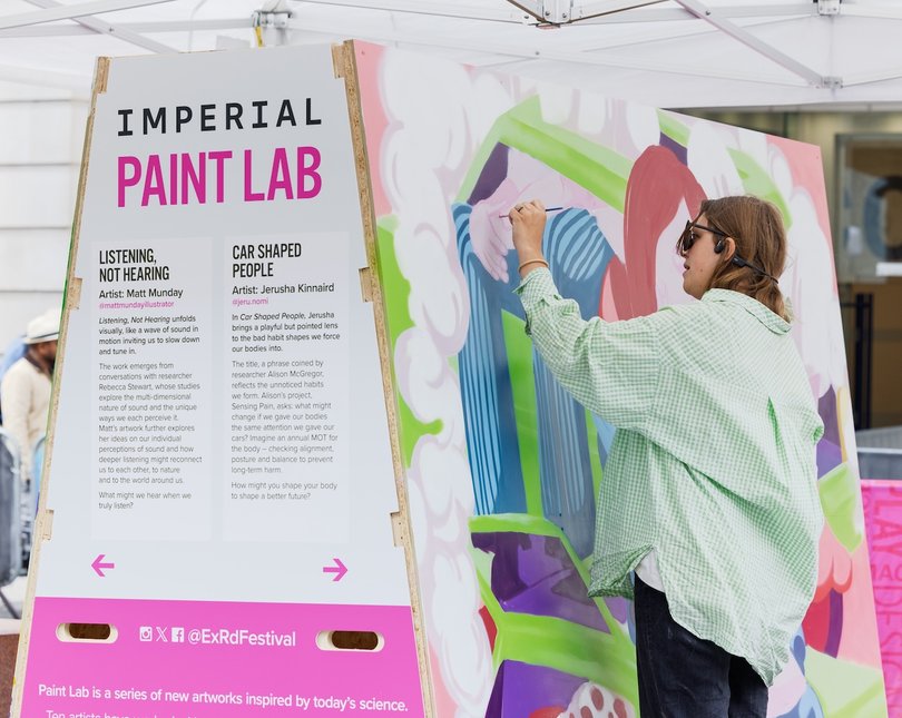 Artist painting on a large outdoor canvas