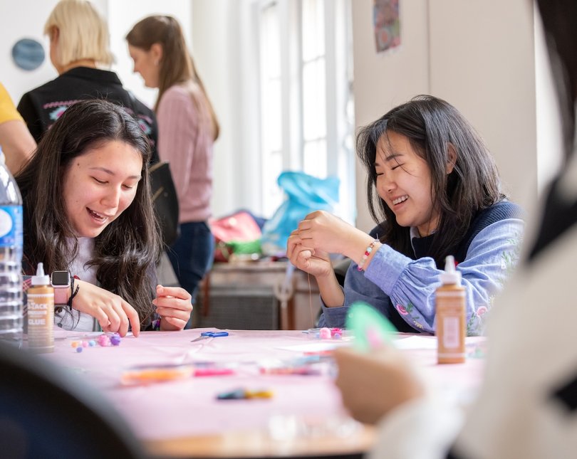 Two adult women smiling and doing a craft exercise