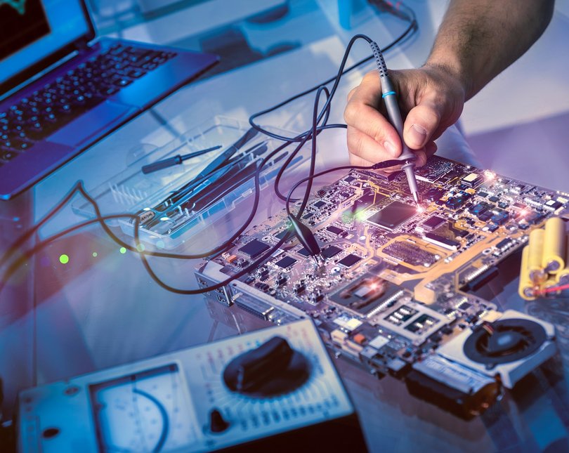 A hand rewires a circuit board