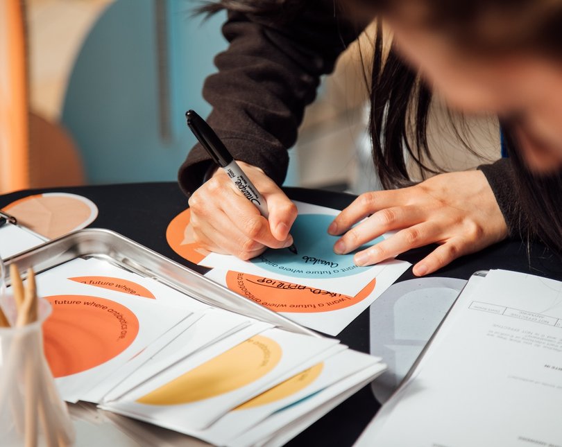 Close up show of someone drawing on a round sticker with a sharpie