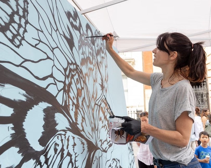 Woman painting a blue butterfly on a large canvas