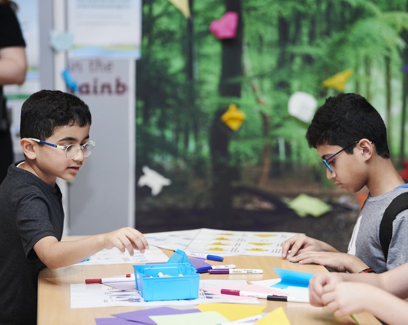 Two young boys sitting at a table doing a crafting activity