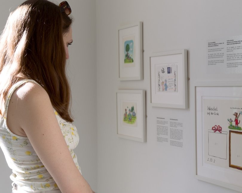 Young woman looking at illustrations in exhibition