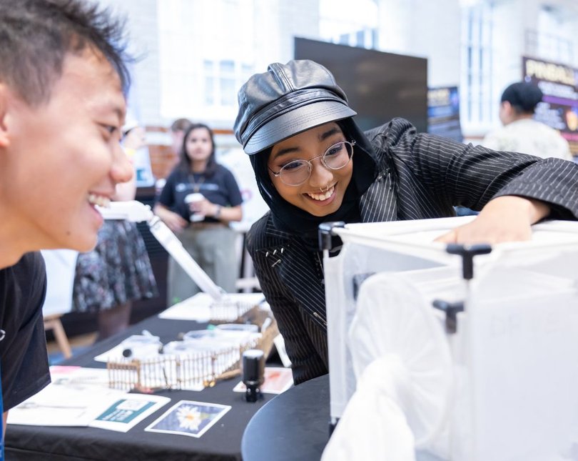 Young person touching white box and talking to researcher